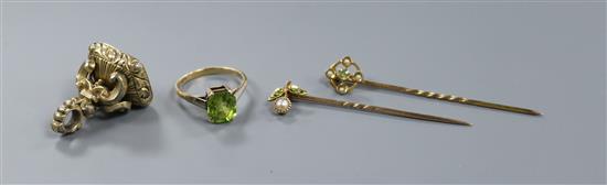 A 15ct gold and single stone peridot ring, two yellow metal and gem set stick pins and a gold plated fob seal.